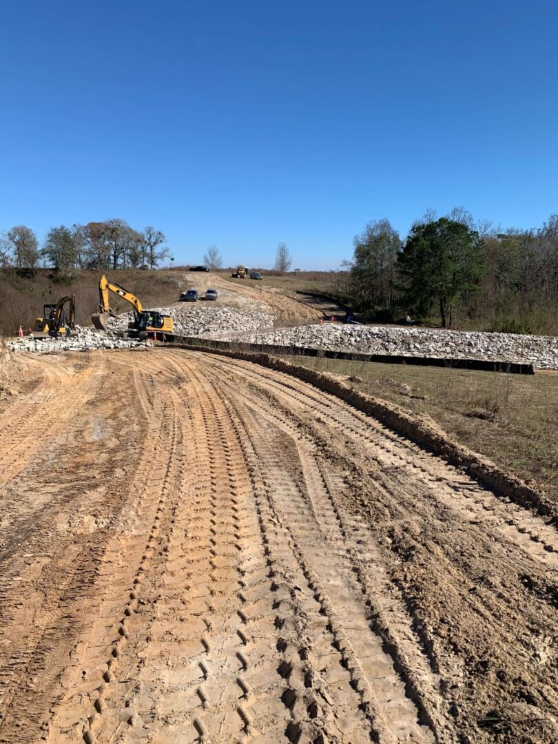 A dirt road with a tractor and bulldozer on it